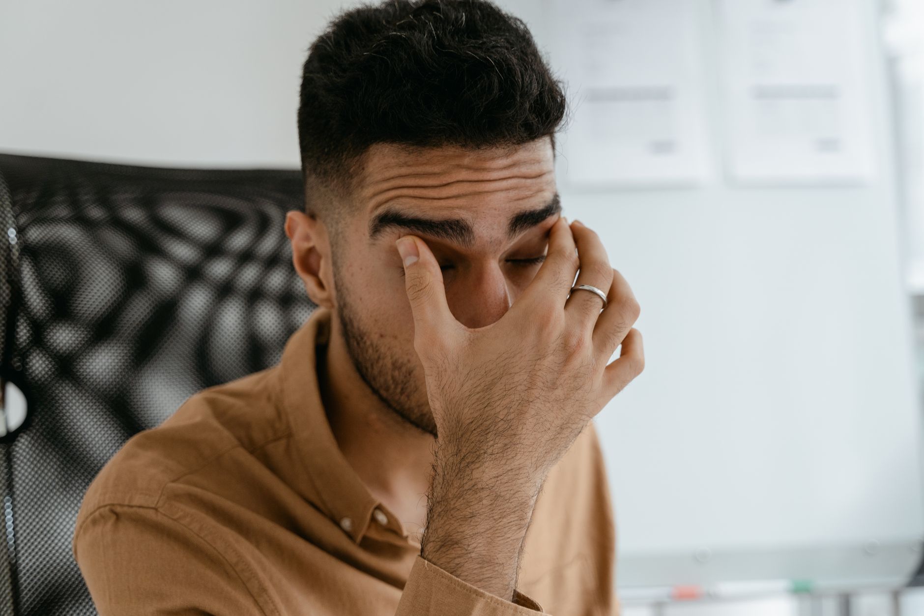 salarié assis à son bureau qui se frotte les yeux de fatigue