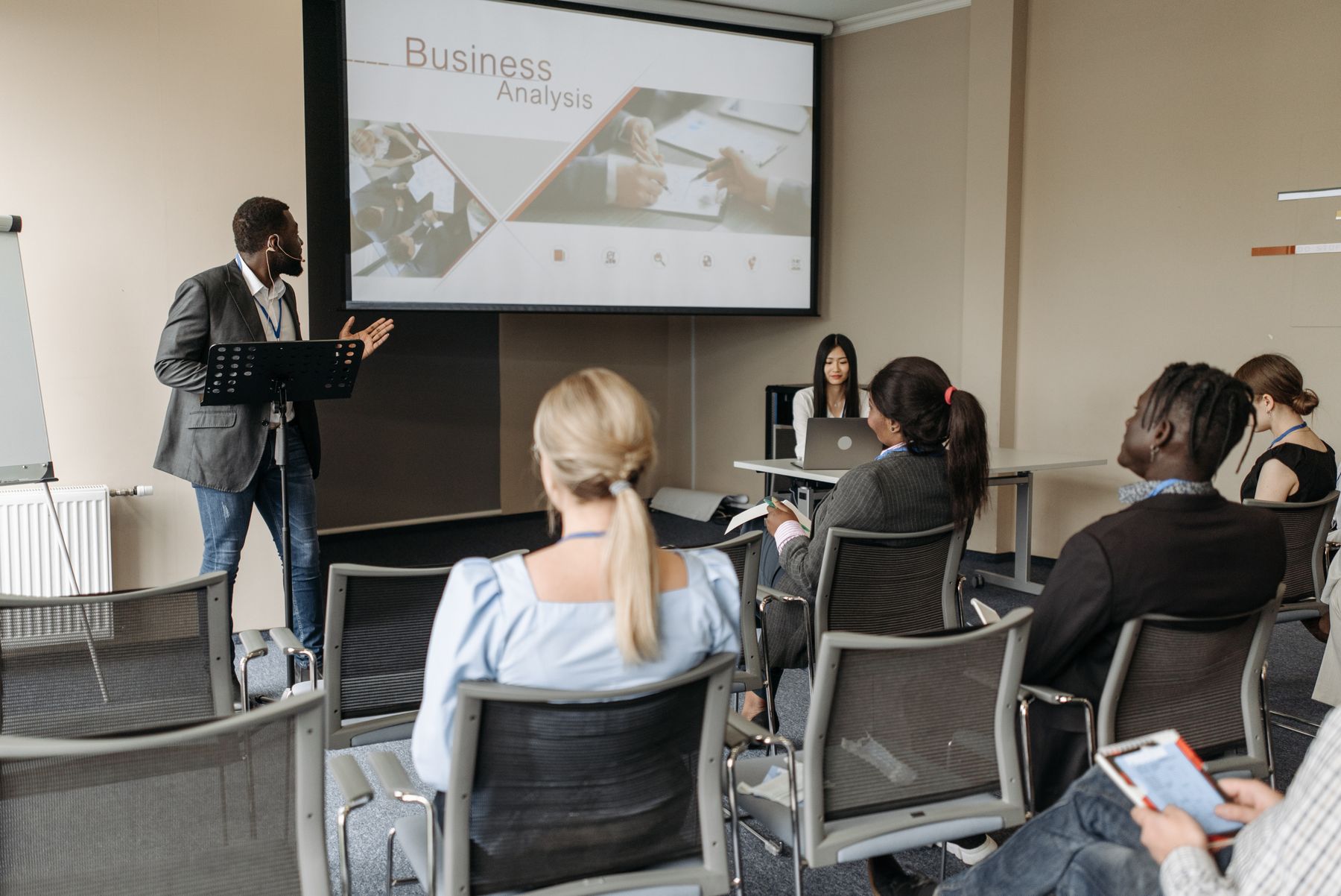 formateur en costume animant une présentation devant un groupe de professionnels en formation