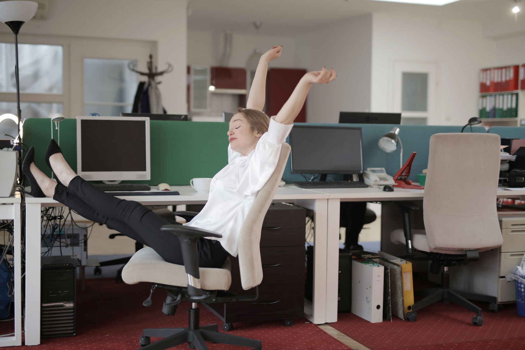 personne en tenue de bureau qui étire doucement les épaules et la nuque assise sur une chaise de travail