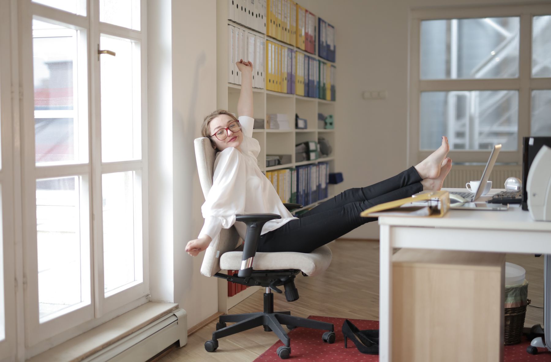 personne debout près d'un bureau qui ouvre la poitrine en étirant les bras vers l'arrière, tenue professionnelle